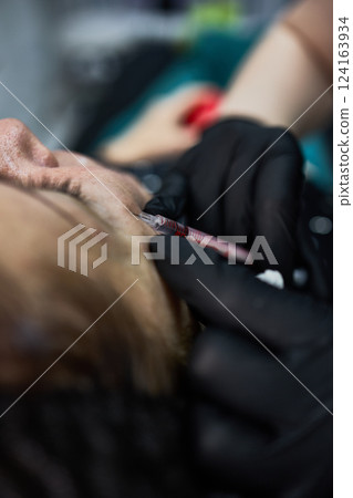Cosmetic procedure with injection on face for beauty enhancement, black gloves, medical treatment, skincare method, aesthetic treatment concept Cosmetic procedure with injection on face for beauty enhancement, black gloves, medical treatment, skincare method, aesthetic treatment concept 124163934
