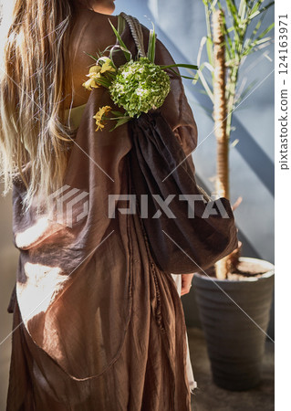 Elegant woman with floral bouquet, draped in brown, sunlight streaming in, elegant fashion statement, natural styling concept Elegant woman with floral bouquet, draped in brown, sunlight streaming in, elegant fashion statement, natural styling concept 124163971