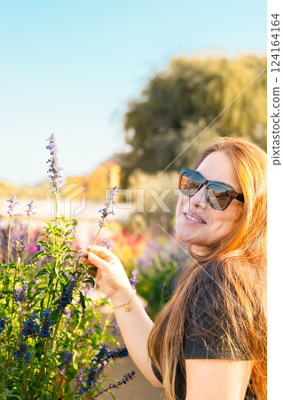Young woman enjoying scent in blooming spring garden. The concept of youth, love, fashion and lifestyle. Young woman enjoying scent in blooming spring garden. The concept of youth, love, fashion and lifestyle. 124164164