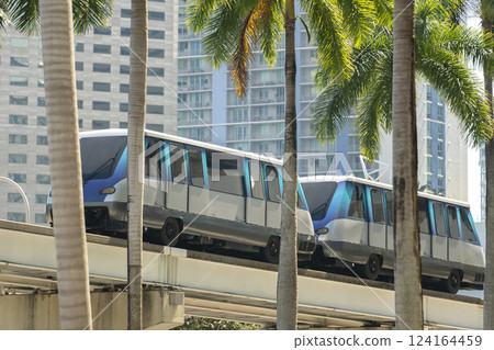 Elevated train public transportation in Miami city downtown district in Florida USA. Metrorail train car on high railroad over street traffic between skyscraper buildings in modern American urban area Elevated train public transportation in Miami city downtown district in Florida USA. Metrorail train car on high railroad over street traffic between skyscraper buildings in modern American urban area 124164459