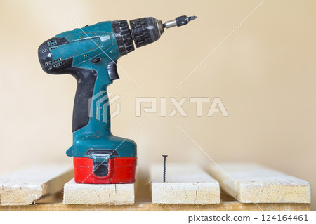 Electric cordless screwdriver and one screw close-up Electric cordless screwdriver and one screw close-up 124164461