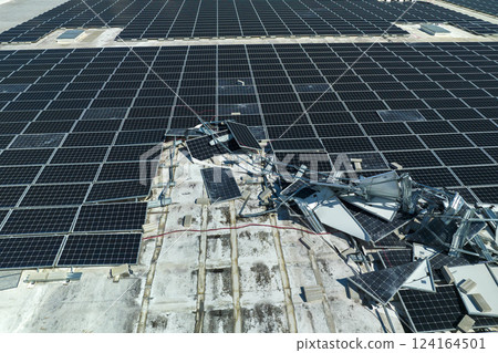 Destroyed by hurricane winds broken down photovoltaic solar panels mounted on industrial building roof for producing green ecological electricity. Consequences of natural disaster in Florida 124164501
