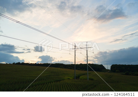 Dark silhouette of high voltage tower with electric power lines at sunrise. 124164511