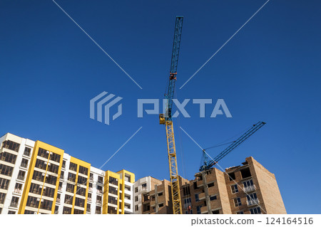 Crane and high rise building under construction against blue sky. Modern architecture background Crane and high rise building under construction against blue sky. Modern architecture background 124164516
