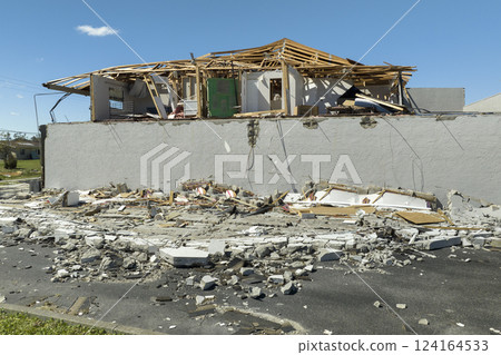 Consequences of natural disaster. Damaged house roof with missing shingles and broken apart walls after hurricane Ian in Florida 124164533