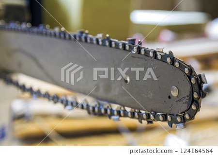 Closeup view of a chainsaw bar and cutting chain at construction site. 124164564