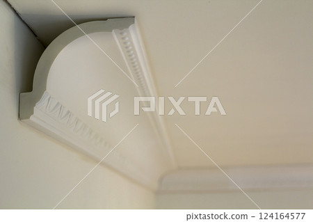 Close-up detail of decoration white molding connected with glue adhesive to wall and ceiling in interior room renovation and reconstruction. 124164577