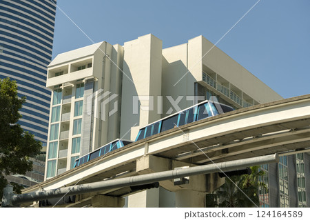 City train car on high railroad over street traffic between skyscraper buildings in modern American megapolis. Urban transportation in downtown district of Miami Brickell in Florida USA City train car on high railroad over street traffic between skyscraper buildings in modern American megapolis. Urban transportation in downtown district of Miami Brickell in Florida USA 124164589