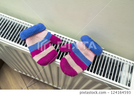 Children's warm hand knitted striped woolen gloves drying on hea Children's warm hand knitted striped woolen gloves drying on hea 124164593