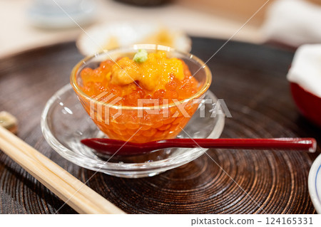Japanese appetizer of salmon roe served in a glass bowl topped with sea urchin and wasabi Japanese appetizer of salmon roe served in a glass bowl topped with sea urchin and wasabi 124165331