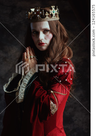 pensive medieval queen in red dress with crown praying 124165575