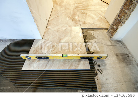 Ceramic tiles and tools for tiler. Floor tiles installation. Home improvement, renovation - ceramic tile floor adhesive, mortar, level 124165596