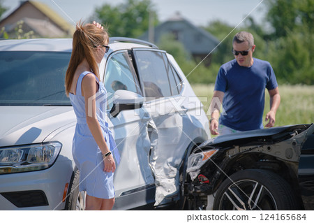 Angry woman and man drivers of heavily damaged vehicles arguing who is guilty in car crash accident on street side. Road safety and insurance concept 124165684