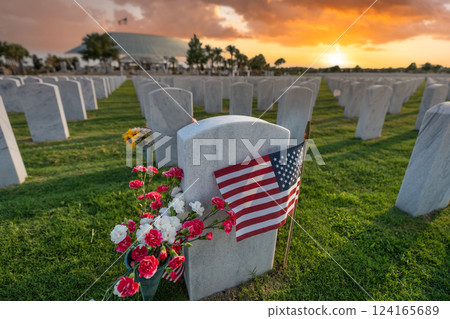 American national military cemetery with rows of white tomb stones with flowers and USA flags on green grass lawn. Memorial Day concept 124165689