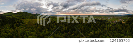Aerial wide panoramic view of dark mountain hills covered with green mixed pine and lush forest in evening. Aerial wide panoramic view of dark mountain hills covered with green mixed pine and lush forest in evening. 124165703