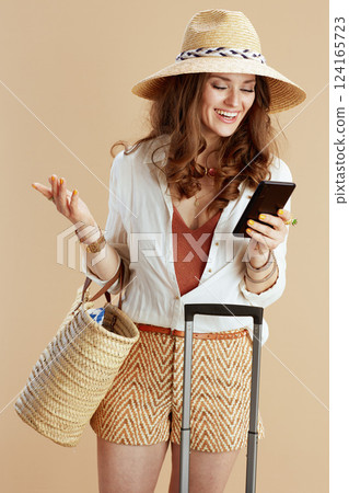 smiling trendy housewife in blouse and shorts isolated on beige 124165723