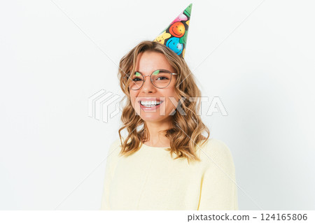 A woman wearing a party hat and glasses is smiling A woman wearing a party hat and glasses is smiling 124165806