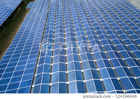Aerial view of solar power plant with blue photovoltaic panels mounted on industrial building roof for producing green ecological electricity. Production of sustainable energy concept. 124166049