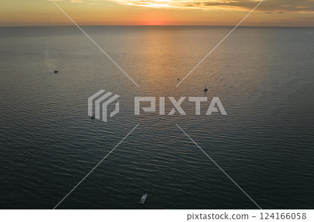 Aerial view of small yachts at sunset floating on sea waves with ripple surface. Motor boats recreation on ocean surface Aerial view of small yachts at sunset floating on sea waves with ripple surface. Motor boats recreation on ocean surface 124166058