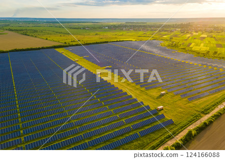 Aerial view of large sustainable electrical power plant with many rows of solar photovoltaic panels for clean ecological electric energy at sunset. Renewable electricity with zero emission concept. Aerial view of large sustainable electrical power plant with many rows of solar photovoltaic panels for clean ecological electric energy at sunset. Renewable electricity with zero emission concept. 124166088