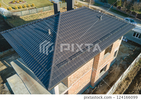 Aerial view of house roof top covered with ceramic shingles. Tiled covering of building under construction Aerial view of house roof top covered with ceramic shingles. Tiled covering of building under construction 124166099