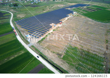 Aerial view of electrical power plant under construction with truck delivering assembly parts for solar panels on metal frame for producing electric energy. Development of renewable electricity 124166115