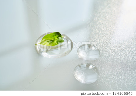 Drop of face serum with green leaf on white background. 124166845