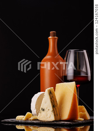 A refined selection of aged cheeses presented on a board, accompanied by a glasses of wine A refined selection of aged cheeses presented on a board, accompanied by a glasses of wine 124167038