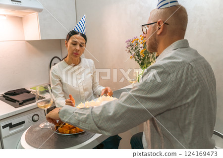 Here's a title attempting to follow all instructions: Birthday Couple Cake Celebration: Intimate home birthday party; man and woman celebrating with cake and candles. 124169473