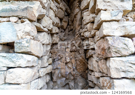 A narrow passage between two large stone walls 124169568