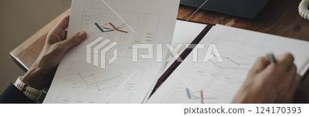 Over the shoulder wide view image of a businesswoman reviewing and reading business sales report 124170393