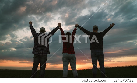 Farmer colleagues raising hands together at sunset field collaboration and teamwork concept back view. Man and woman agronomist agricultural workers celebrate success win victory triumph outdoor Farmer colleagues raising hands together at sunset field collaboration and teamwork concept back view. Man and woman agronomist agricultural workers celebrate success win victory triumph outdoor 124170732