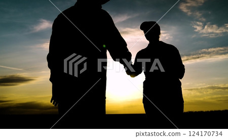 Two agricultural workers silhouette shaking hands working as team at dramatic picturesque sunset sky. Man and woman farmer agronomist colleagues handshaking harvest analyzing use tablet nature outdoor Two agricultural workers silhouette shaking hands working as team at dramatic picturesque sunset sky. Man and woman farmer agronomist colleagues handshaking harvest analyzing use tablet nature outdoor 124170734