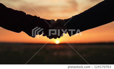 Handshake at sunset silhouette in park field. Hand shake two farmers business people on background of setting sun in meadow making deal conclusion of transaction bargaining. Agricultural business. Handshake at sunset silhouette in park field. Hand shake two farmers business people on background of setting sun in meadow making deal conclusion of transaction bargaining. Agricultural business. 124170763