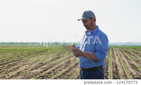 Businessman digital agricultural farmer with tablet. Professional businessman farmer male guy with serious focused look using technological digital tablet for efficient agricultural agrarian business. Businessman digital agricultural farmer with tablet. Professional businessman farmer male guy with serious focused look using technological digital tablet for efficient agricultural agrarian business. 124170773