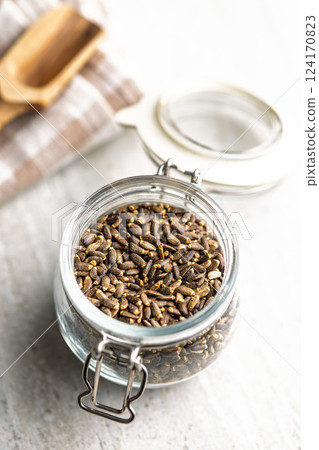 Milk thistle seeds in jar on kitchen table. 124170823