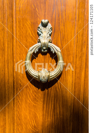 Closed wooden vintage door with golden old knocker in hot summer time. Vignette look. Vintage background.  124171105
