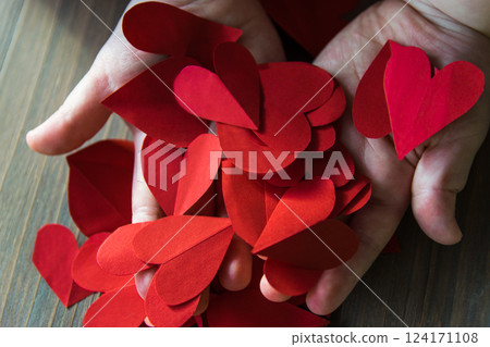 Red hearts from paper in childs hands. A gift for Valentines Day and Mothers Day. 124171108