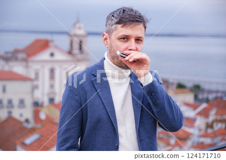 Man plays harmonica outdoors in city street 124171710