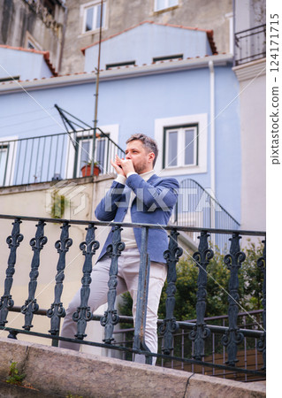 Man plays harmonica outdoors in city street 124171715