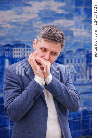 Man plays harmonica outdoors in city street 124171725