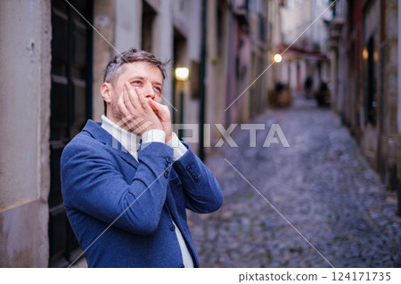 Man plays harmonica outdoors in city street 124171735