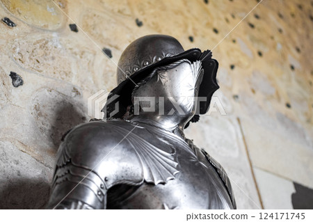 Close up view of medieval shiny armor and white stone wall in background. 124171745
