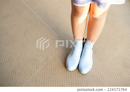 Short rain boots for kids. A fifth-grade girl is wearing light blue rain boots. 124171764