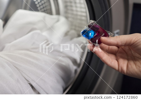 Using Laundry Detergent Pods While Doing Laundry in the Washing Machine with Clothes 124172860