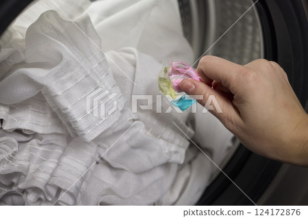 Using Laundry Detergent Pods While Doing Laundry in the Washing Machine with Clothes 124172876