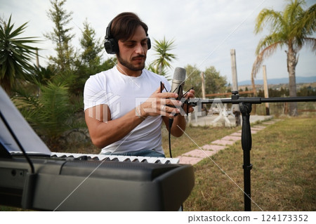 Singer Author Sets Up The Microphone And Sings Playing The Keyboard Singer Author Sets Up The Microphone And Sings Playing The Keyboard 124173352