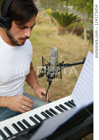 Singer Author Sets Up The Microphone And Sings Playing The Keyboard Singer Author Sets Up The Microphone And Sings Playing The Keyboard 124173454