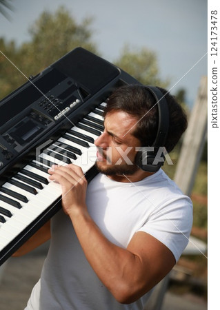 Pianist Man Walks Playing Musical Keyboard On Shoulder In Nature Of Sicily 124173478