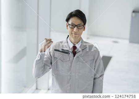 A man in his 40s in work clothes making a fist pump while looking at the camera 124174758
